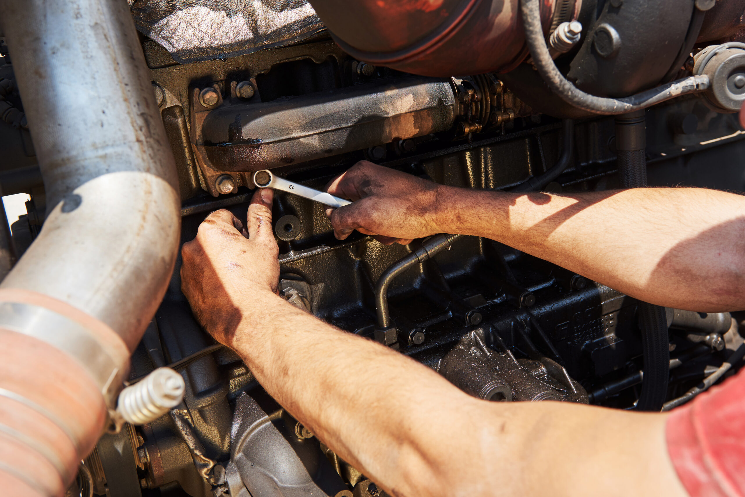 Záběr na ruce mechanika, který rozdělává motor