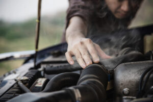 Muž, který kontroluje motor auta, ze kterého se kouří.