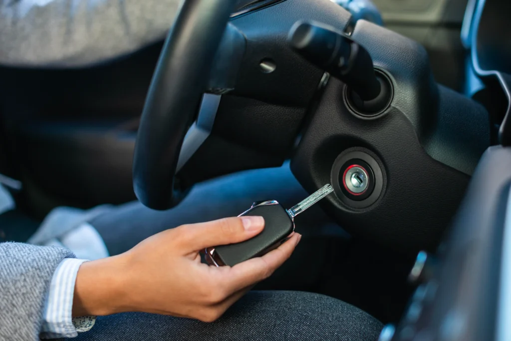 Detail ruky otáčející klíčkem v zapalování automobilu, připravený ke startování motoru.